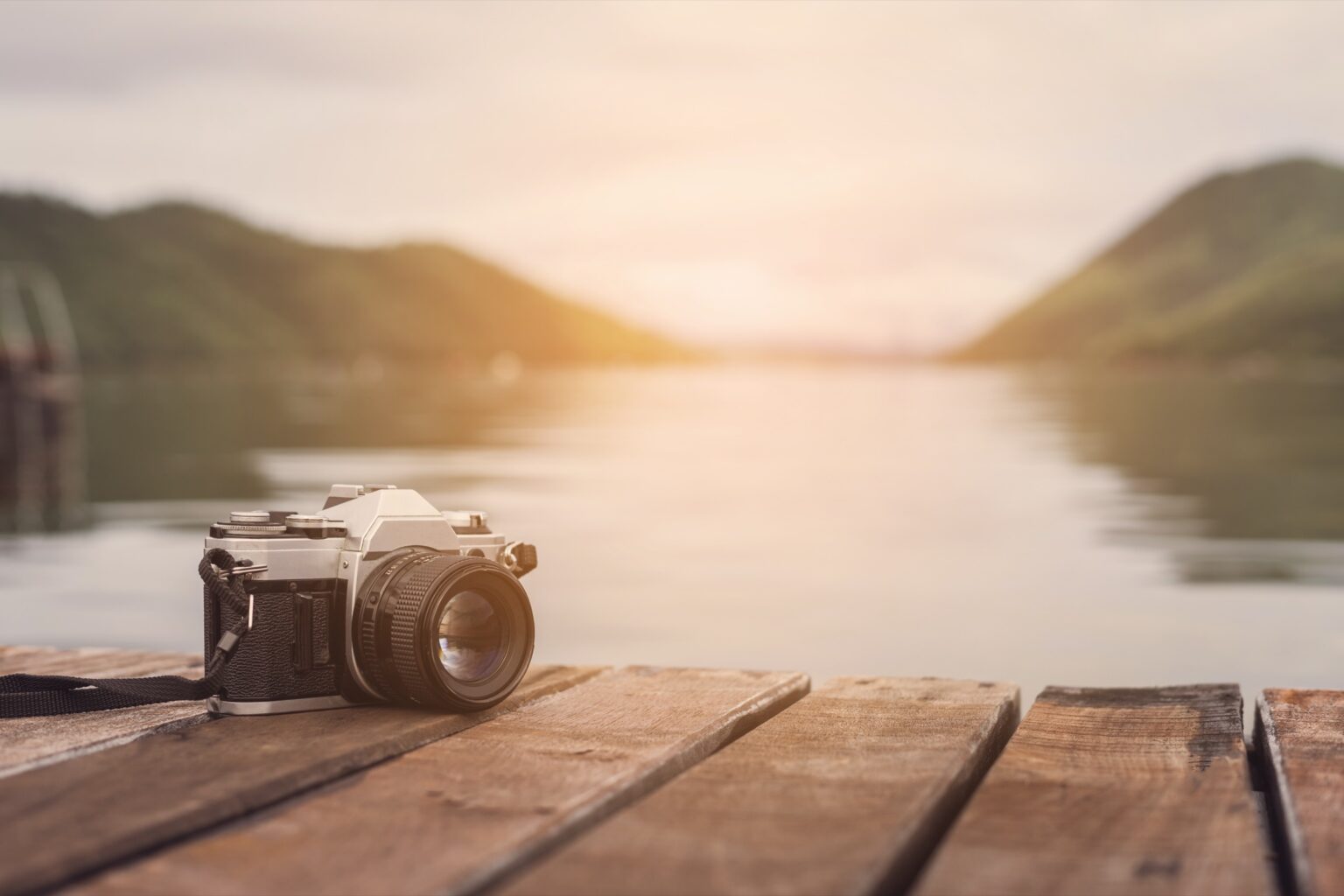 Analoge Kamera auf einem Holzsteg am See im Abendlicht